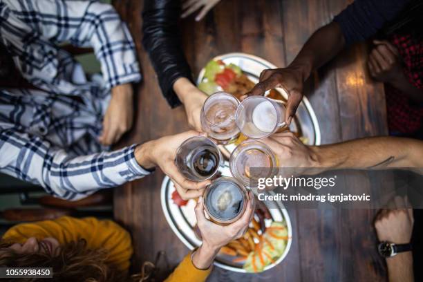 verschiedene arten von bier - friends toasting above table stock-fotos und bilder