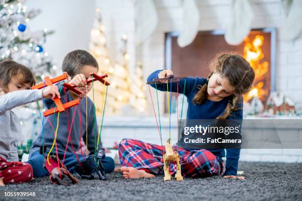 three kids playing with their wooden puppet toys on christmas morning - area rug stock pictures, royalty-free photos & images