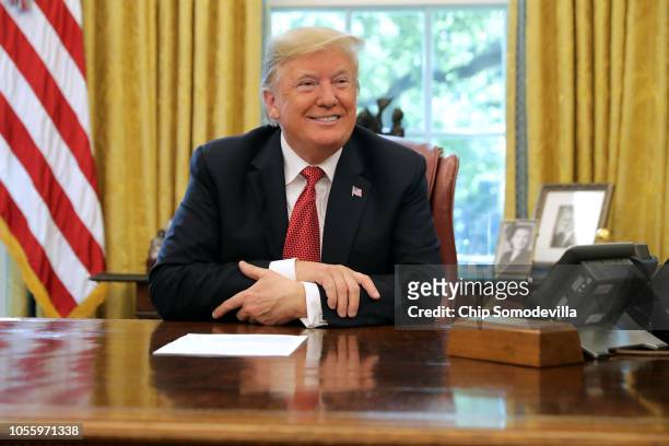 President Donald Trump talks to reporters while hosting workers and members of his cabinet for a meeting in the Oval Office at the White House...