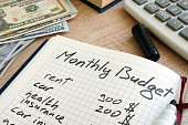 Note pad with monthly budget calculations and money.