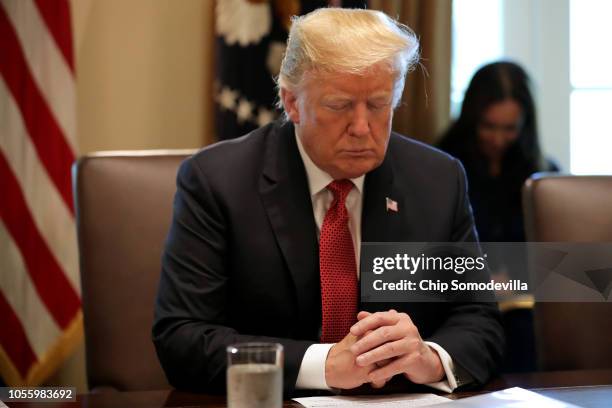 President Donald Trump closes his eyes during a prayer before a meeting of his cabinet in the Cabinet Room at the White House October 17, 2018 in...