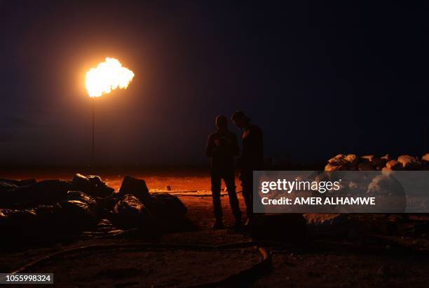 Picture taken on October 31, 2018 shows two workers at a primitive oil facility in the town of Zardana in the countryside of the northwestern Syrian...