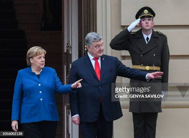 Ukrainian President Petro Poroshenko and German Chancellor Angela Merkel look on and extend their arms during the welcoming ceremony before their...
