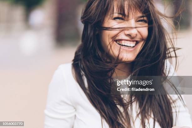 smiling woman on a windy day - beautiful woman in the city imagens e fotografias de stock