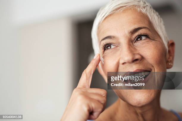 portrait of a senior woman - moisturiser stock pictures, royalty-free photos & images