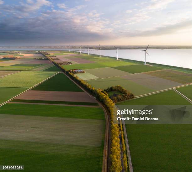 aerial view of a man-made landscape in the netherlands with farms, wind turbines, water and polders. - friesland stock pictures, royalty-free photos & images