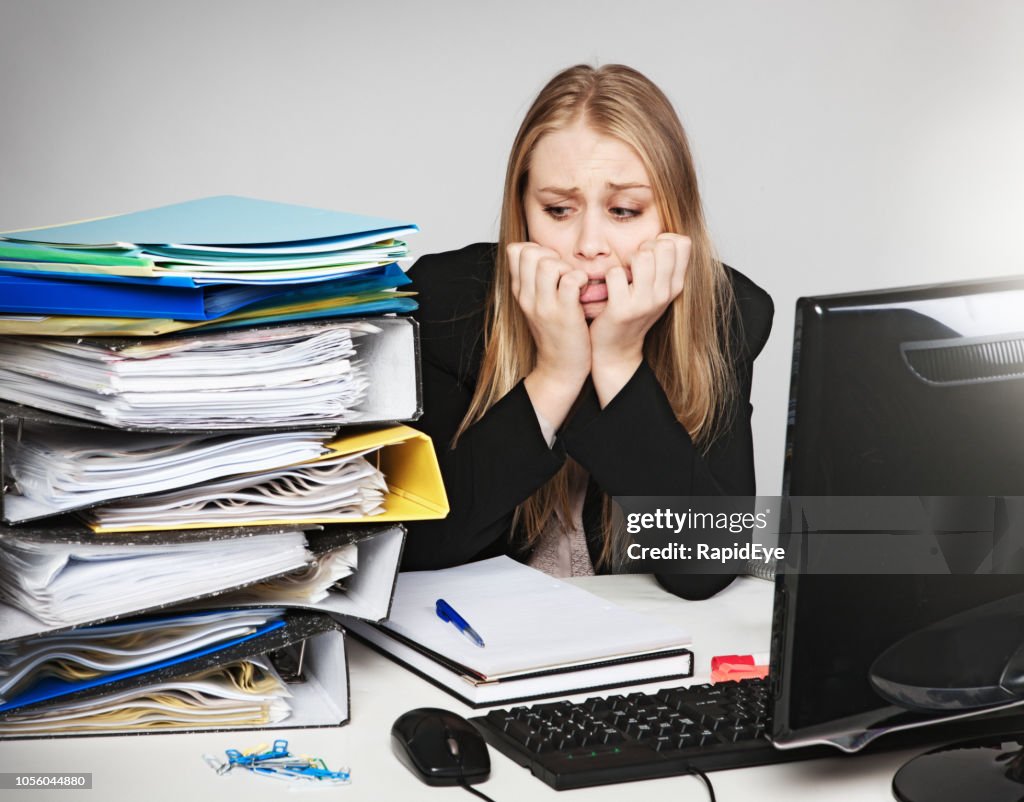 Verzweifelte junge blonde Büroangestellte mit zuviel Arbeit