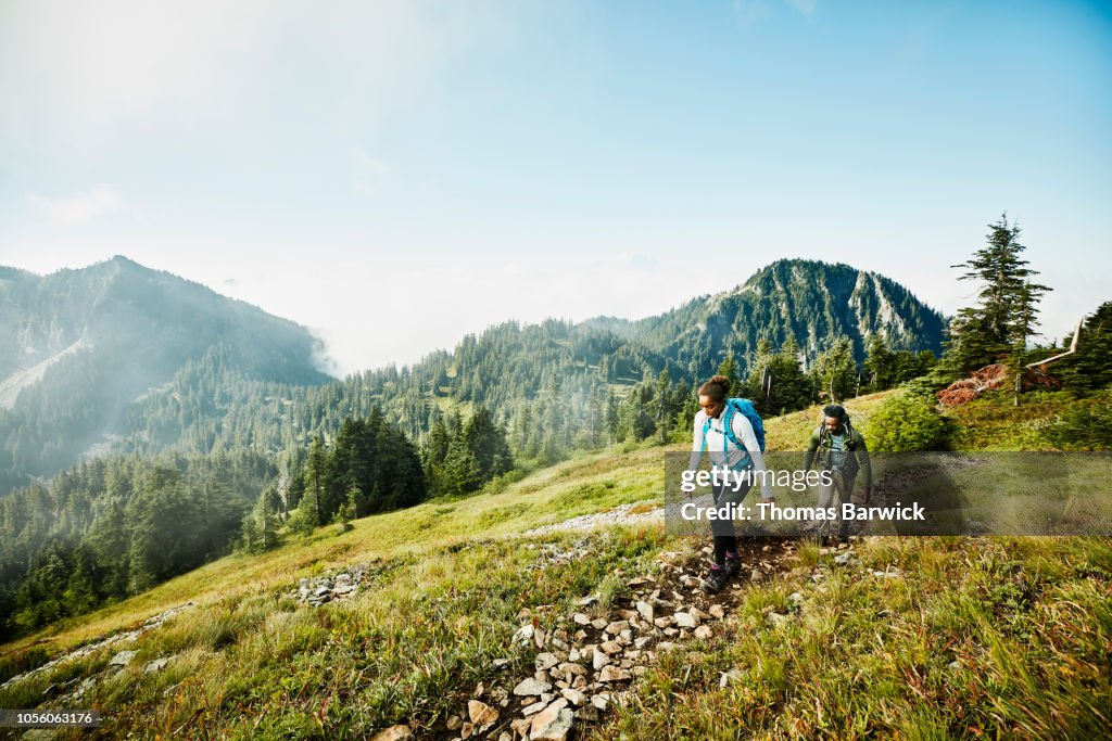 Daughter leading father on morning hike up mountainside