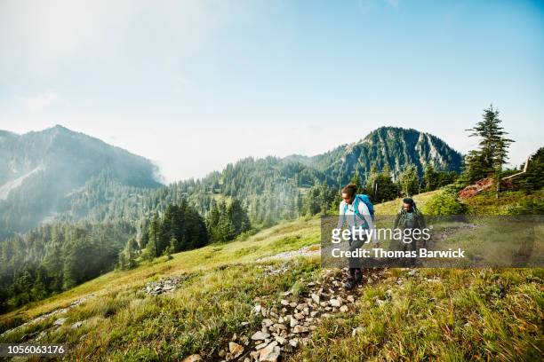 Daughter leading father on morning hike up mountainside