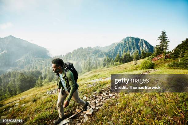 man on early morning hike up mountainside - adventure man stock pictures, royalty-free photos & images