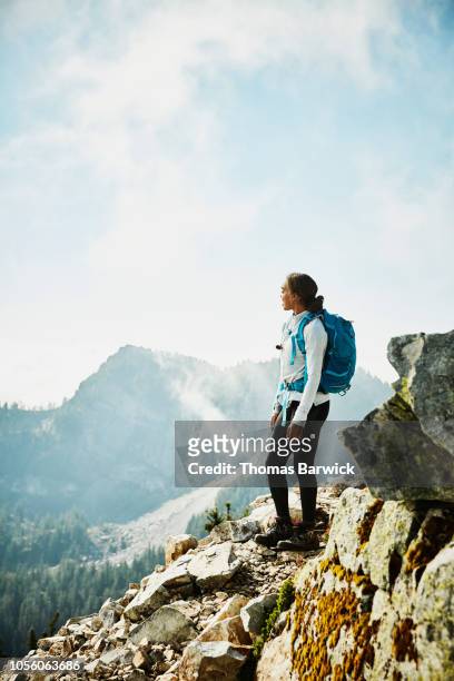 young woman enjoying view from outlook during hike in mountains - american girl alone stock-fotos und bilder