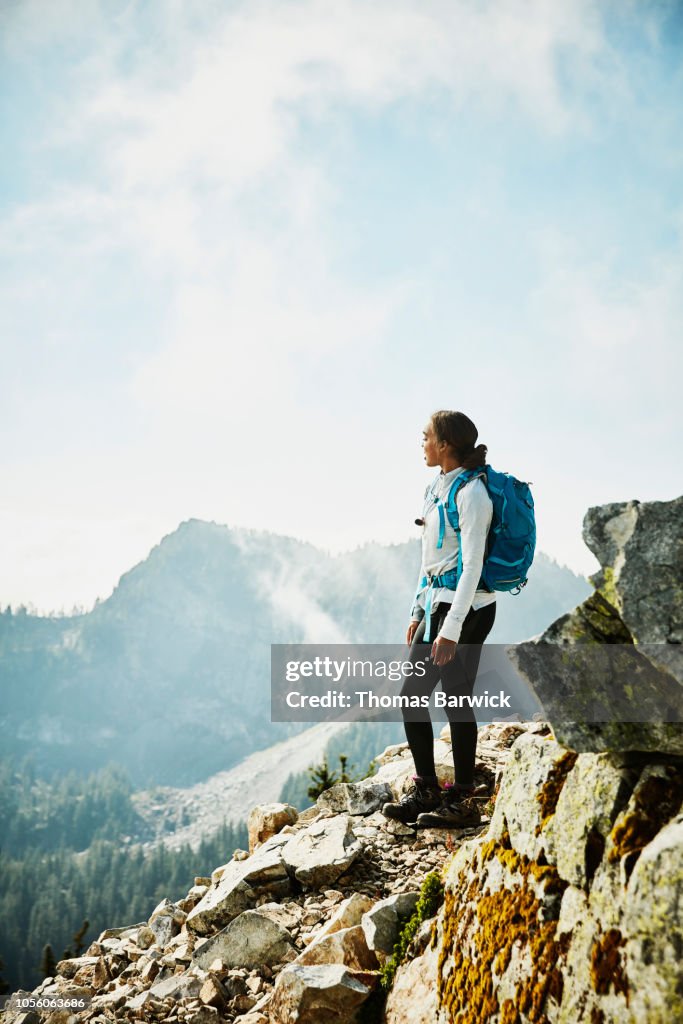 Young woman enjoying view from outlook during hike in mountains