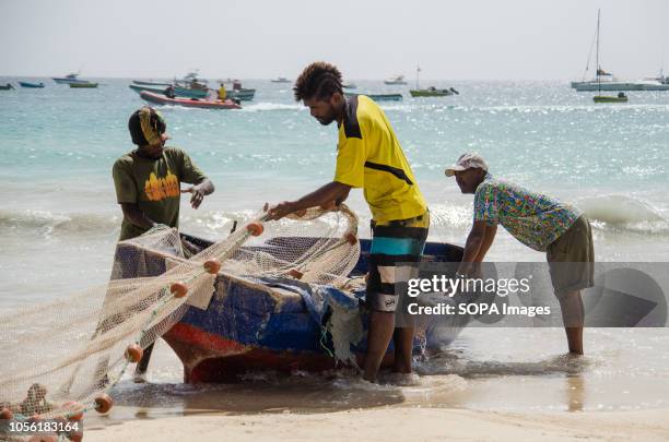 Fishermen clean their nets after arriving from the Atlantic Ocean. Cape Verde, is a nation on a volcanic archipelago off the northwest coast of...