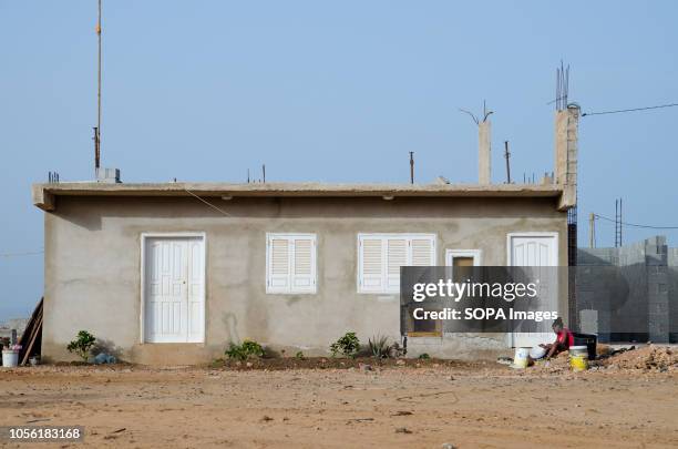 Woman is seen sitting in front of her concrete house. Cape Verde, is a nation on a volcanic archipelago off the northwest coast of Africa.