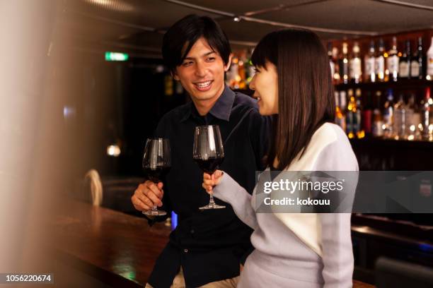 men and women drinking while standing at a bar counter - young couple date night wine stock pictures, royalty-free photos & images