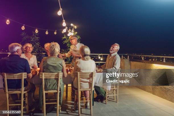 senior new year rooftop party - new year's eve dinner stock pictures, royalty-free photos & images