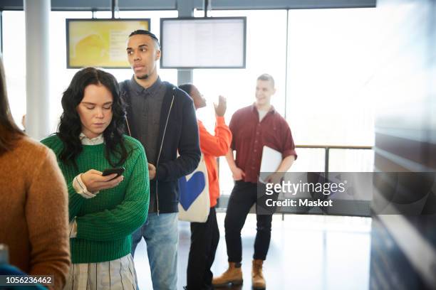 male and female students standing in queue at university - line up stockfoto's en -beelden