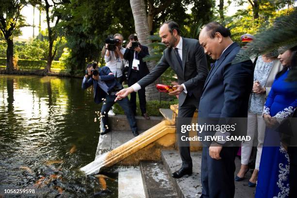 French Prime Minister Edouard Philippe feeds fish as his Vietnamese counterpart Nguyen Xuan Phuc looks on during a tour of the Presidential Palace in...