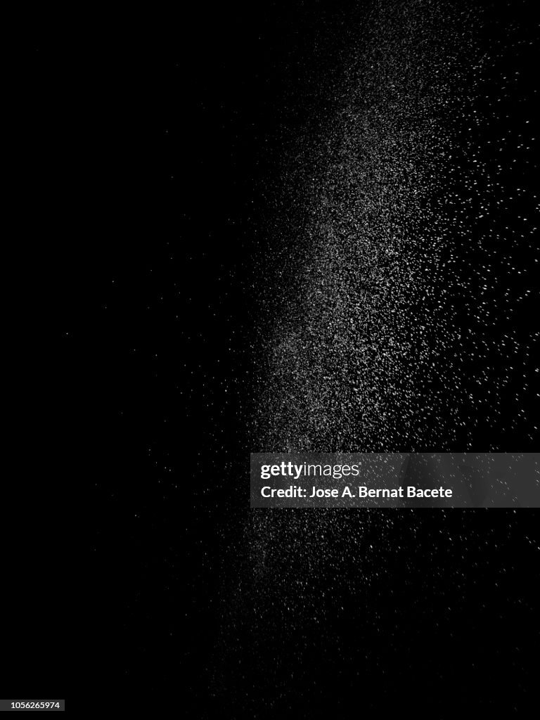 Explosion by an impact of a cloud of particles of powder of color white on a black background.