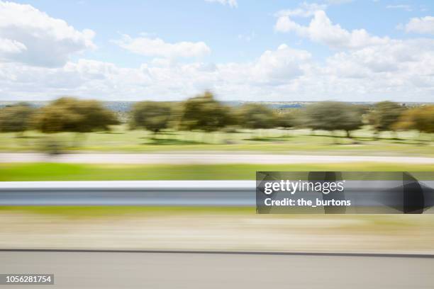 blurred sideview out of car`s window on crash barrier and landscape on a motorway - crash barrier stock pictures, royalty-free photos & images