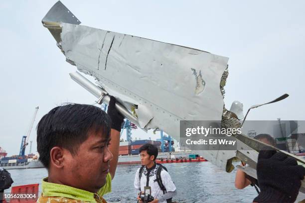 Man carries a piece of the Lion Air flight JT 610 wreckage which is being moved to another location for further investigation at the Tanjung Priok...