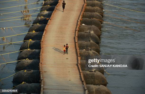 Indian children walk on a newly constructed temporary pontoon bridge built over the river Ganges for the upcoming Kumbh Mela festival, in Allahabad...