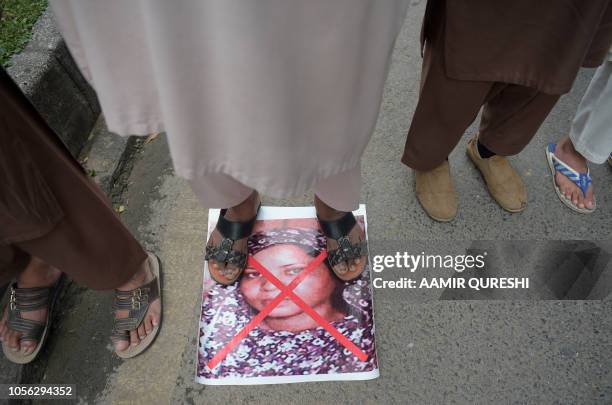 Pakistani supporter of the Ahle Sunnat Wal Jamaat , a hardline religious party, stands over an image of Christian woman Asia Bibi as they march...