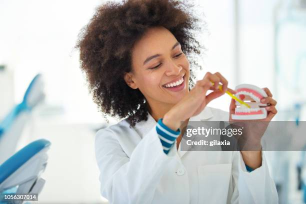 dentista que muestra la forma correcta de cepillarse los dientes. - dentadura postiza fotografías e imágenes de stock