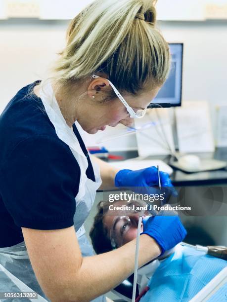 dental hygenist working on patients teeth - dentist stock pictures, royalty-free photos & images