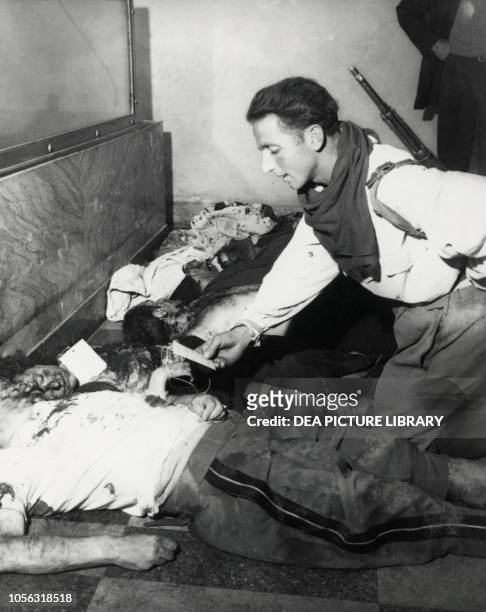 Partisan checking the cards on Benito Mussolini and Claretta Petacci's bodies, Milan morgue, April 30 Italy, World War II, 20th century.
