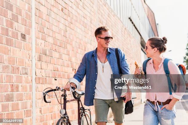 young couple with bicycle walking and talking - summer press day ストックフォトと画像