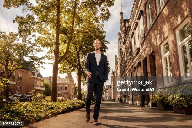 netherlands, venlo, confident businessman walking on pavement - low angle view ストックフォトと画像