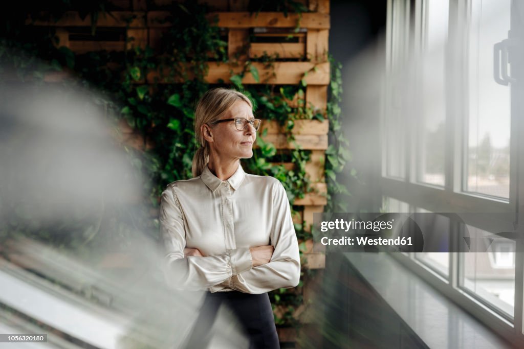 Businesswoman in green office looking out of window