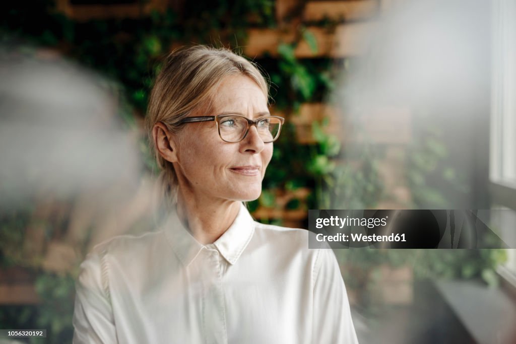 Businesswoman in green office looking out of window