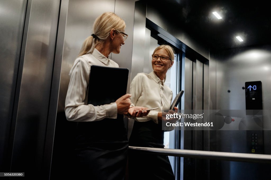 Smiling businesswoman looking in mirror in elevator
