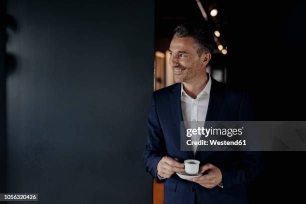 smiling businessman with espresso cup looking sideways - espresso drink stock pictures, royalty-free photos & images
