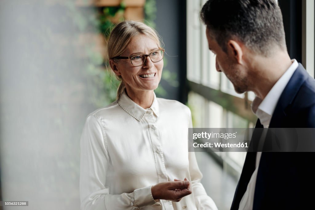 Businessman and businesswoman talking at the window
