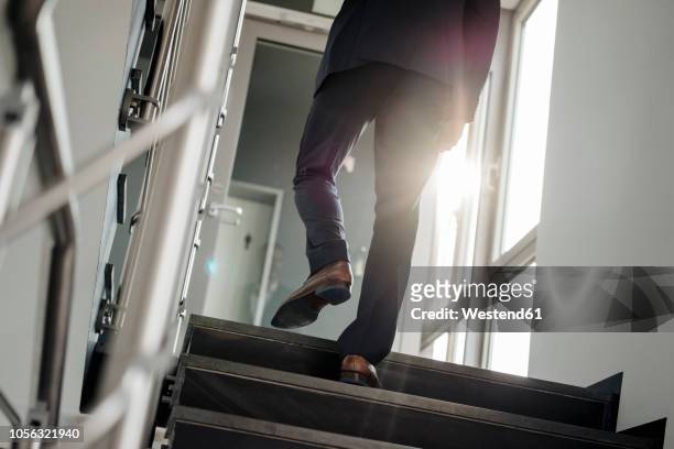 legs of businessman walking upstairs - hinauf bewegen stock-fotos und bilder