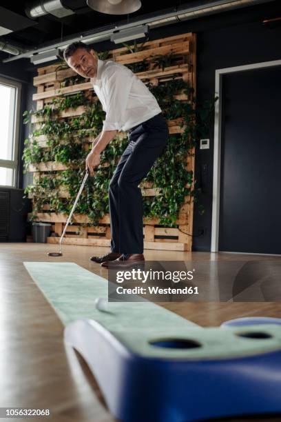 businessman playing golf in office - miniature golf stock pictures, royalty-free photos & images