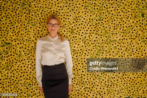 portrait of businesswoman standing at wall with sunflowers - rodeando - fotografias e filmes do acervo