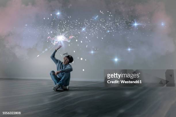 young man in empty apartment sitting on the floor using virtual reality glasses, composite - idee stock-fotos und bilder