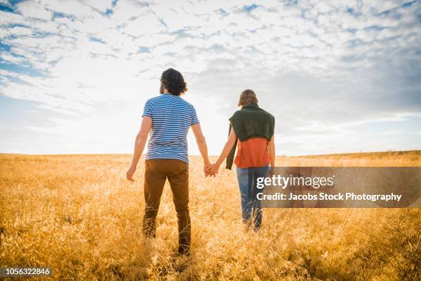 couple together in field - young couple enjoying a walk through grassland stock pictures, royalty-free photos & images