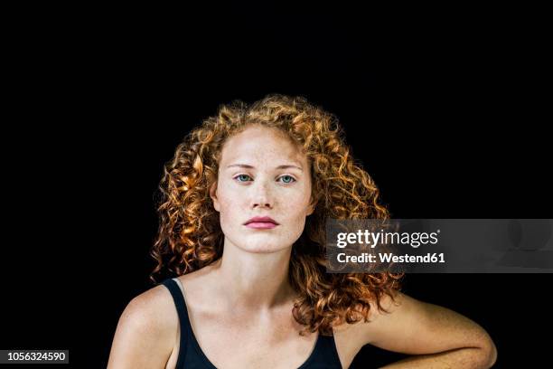 portrait of freckled young woman with curly red hair in front of black background - young woman looking at camera stock pictures, royalty-free photos & images