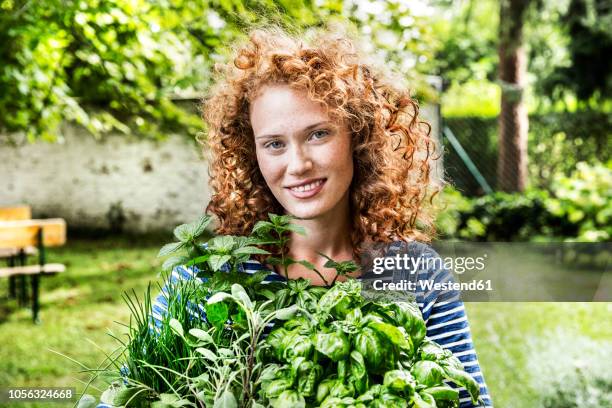 portrait of young woman with fresh herbs in garden - heilpflanze stock-fotos und bilder