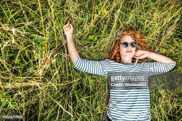portrait of young woman relaxing on a meadow - low key stock-fotos und bilder