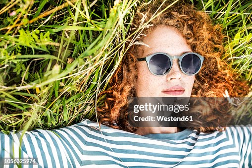 Portrait of young woman relaxing on a meadow wearing sunglasses Portrait of young woman relaxing on a meadow wearing sunglasses