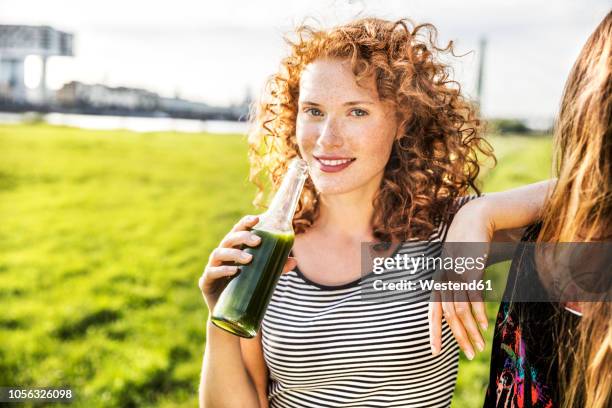 germany, cologne, portrait of redheaded young woman enjoying beverage - cologne bottle stock pictures, royalty-free photos & images