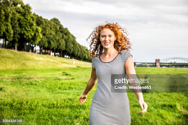 germany, cologne, portrait of smiling young woman on meadow - vestido a rayas fotografías e imágenes de stock
