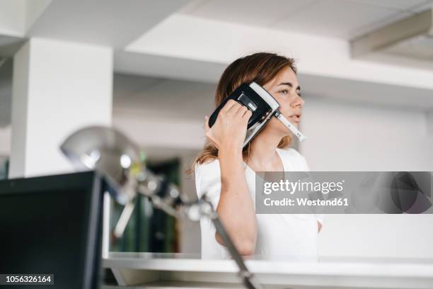 woman holding a hole punch on her ear - fehler stock-fotos und bilder