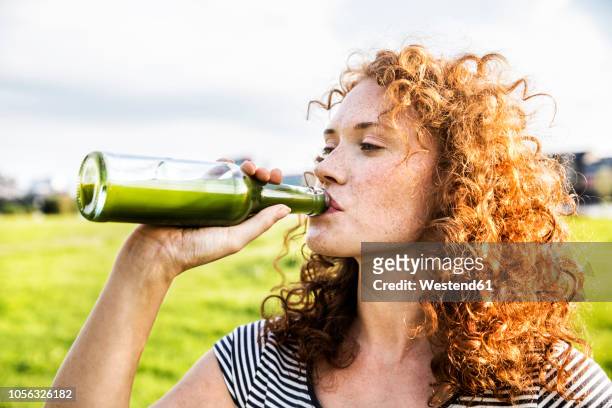 portrait of redheaded young woman drinking beverage - drink stock-fotos und bilder